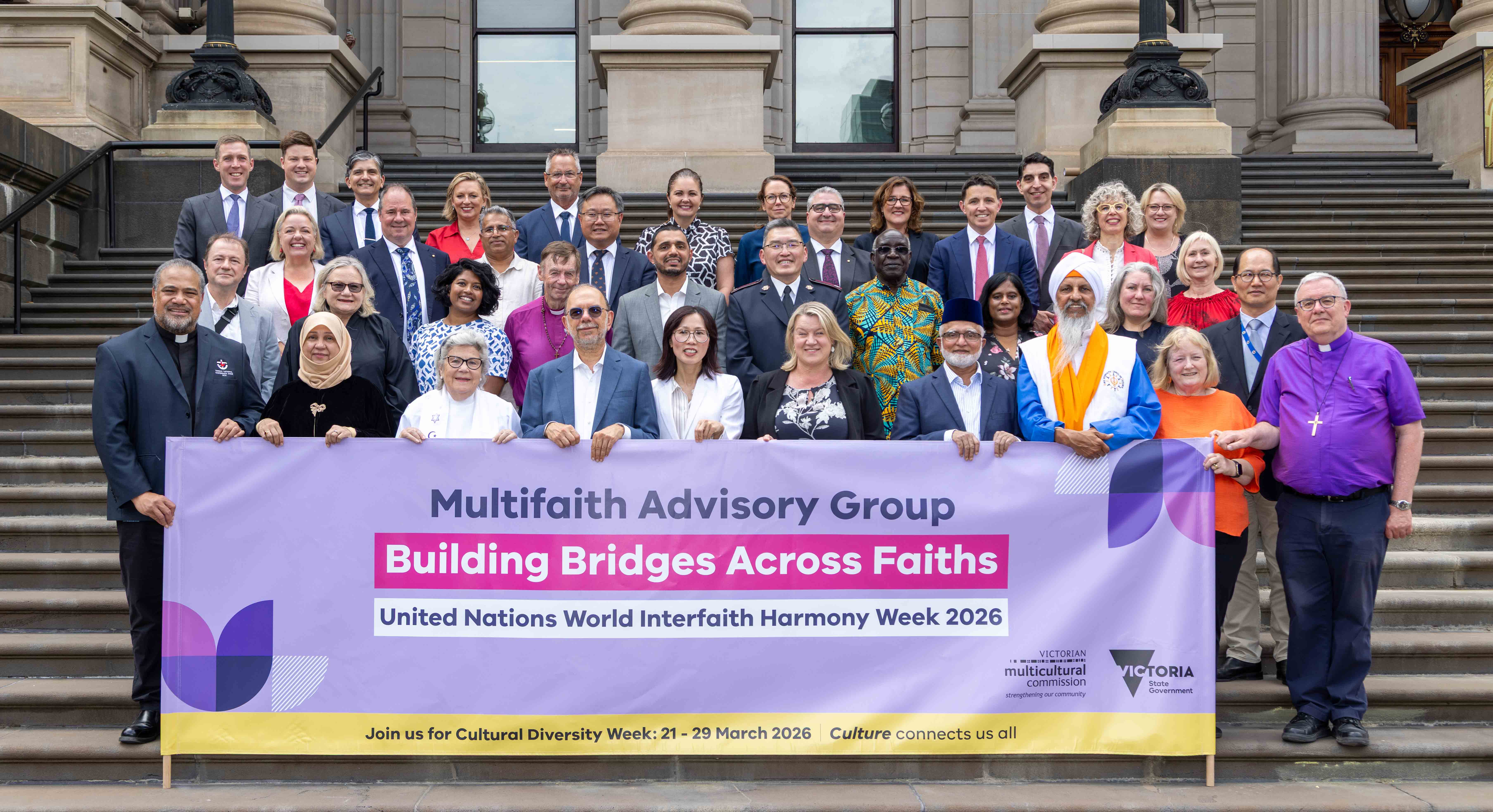 Members of the Multifaith Advisory Group and MPs stand with a banner: Building Bridges Across Faithsaiths